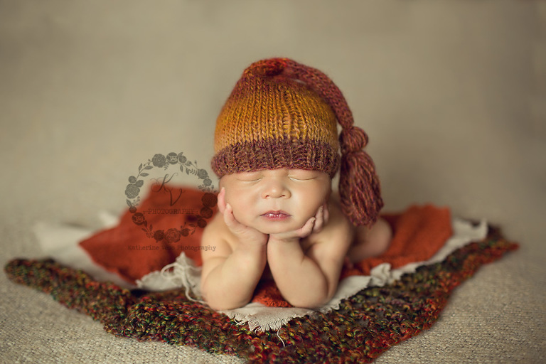 baby boy in orange, chin in hands