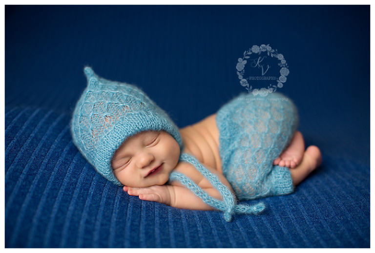 smiling newborn boy in blue pants/hat