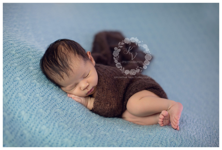 newborn baby boy wrapped in cute snuggley pose